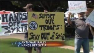 Author holding up signs at a September 2013 anti-war protest in Texas: "Support our troops - Stay out of Syria". (Screenshot from Texas regional news footage)