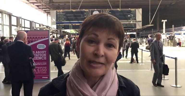 Caroline Lucas speaking to the camera at a train station