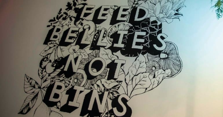 Artwork from Real Junk Food MCR that reads 'FEED BELLIES NOT BINS'