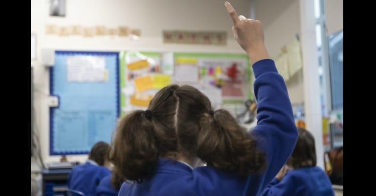 Child raising hand in classroom