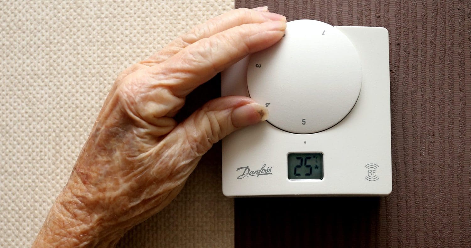 An old person's hand on a thermostat