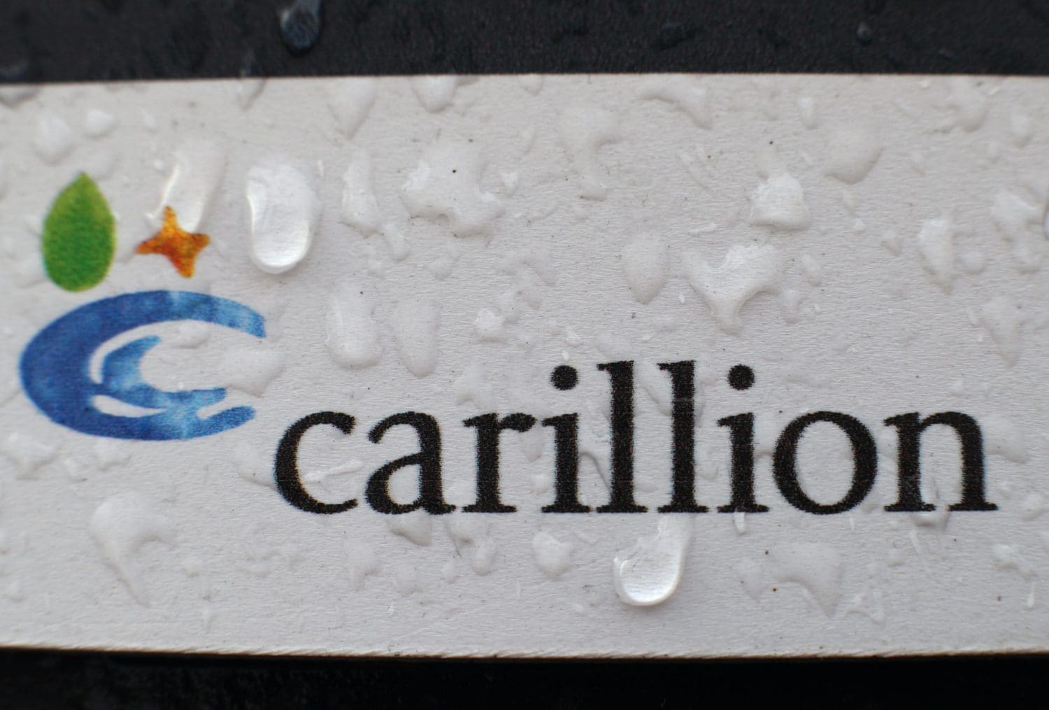 The Carillion logo with rain water on it