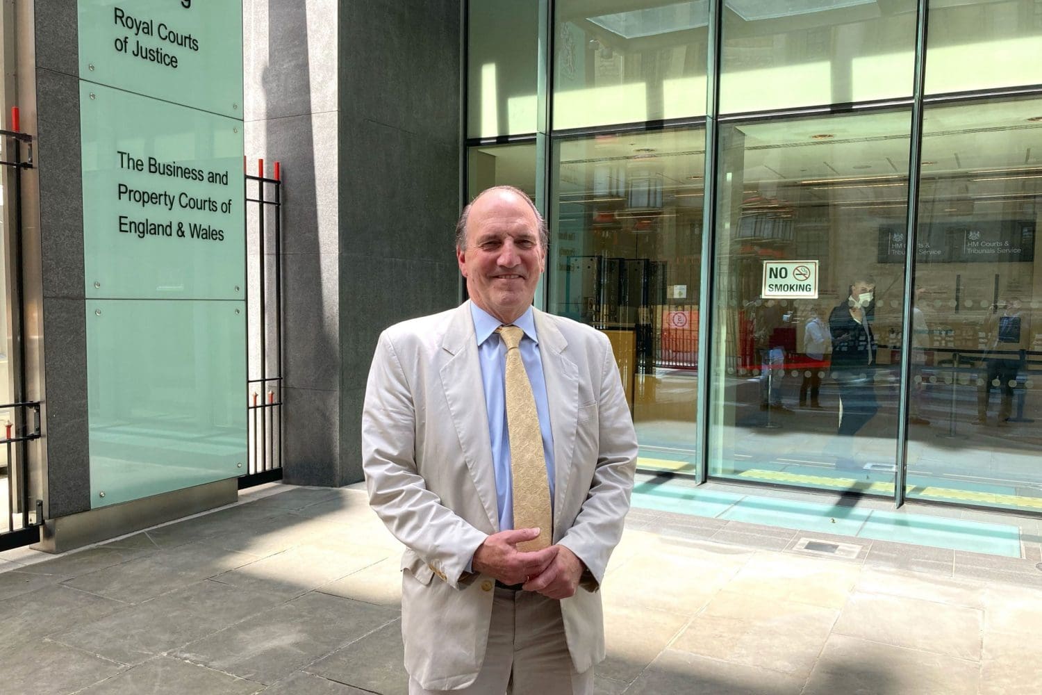 Victor over The Sun Simon Hughes smiling in front of a court room