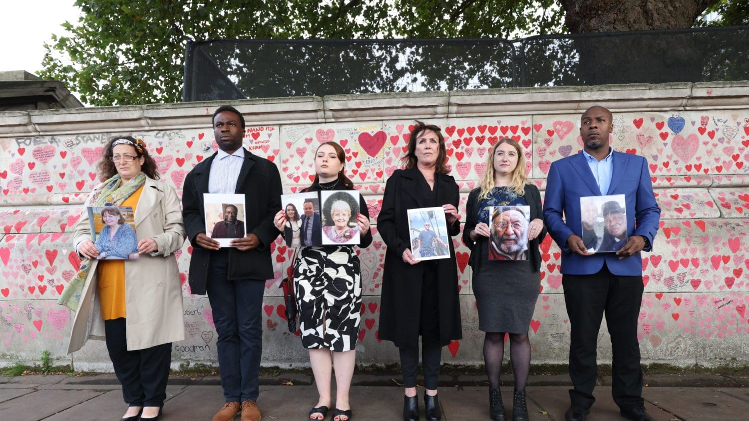 Members of The Covid-19 Bereaved Families for Justice group holding up pictures of family members