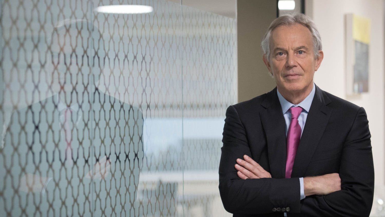 Tony Blair standing to the right with his arms crossed