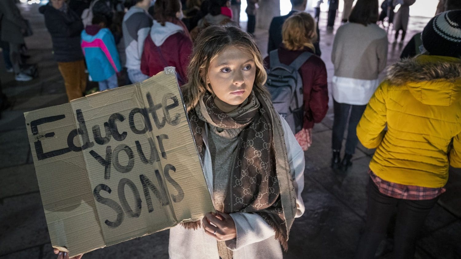 A protester holding a sign which reads "educate your sons"