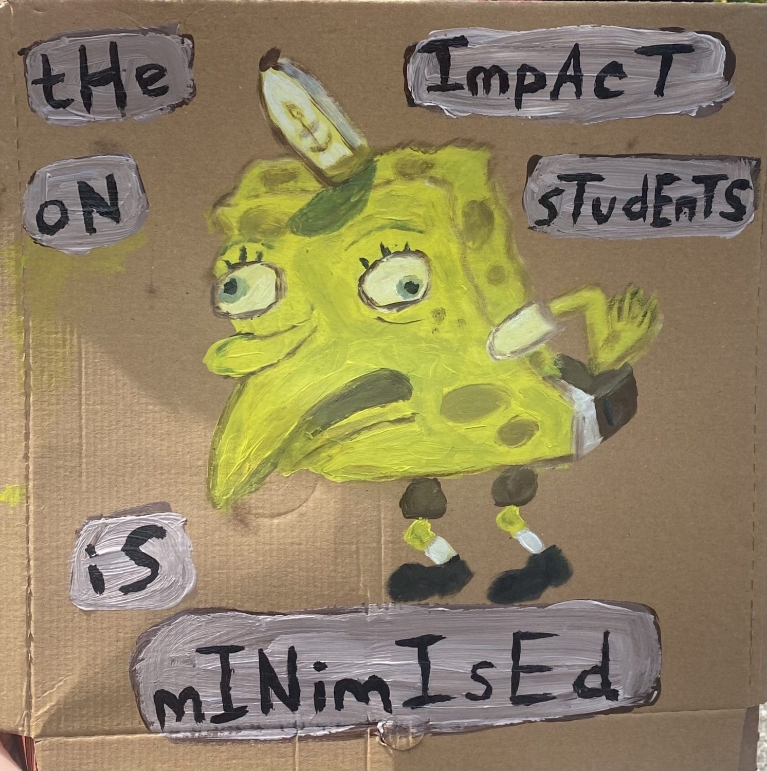 A placard with a cartoon of Sponebob Squarepants that reads "the impact on students is minimised"