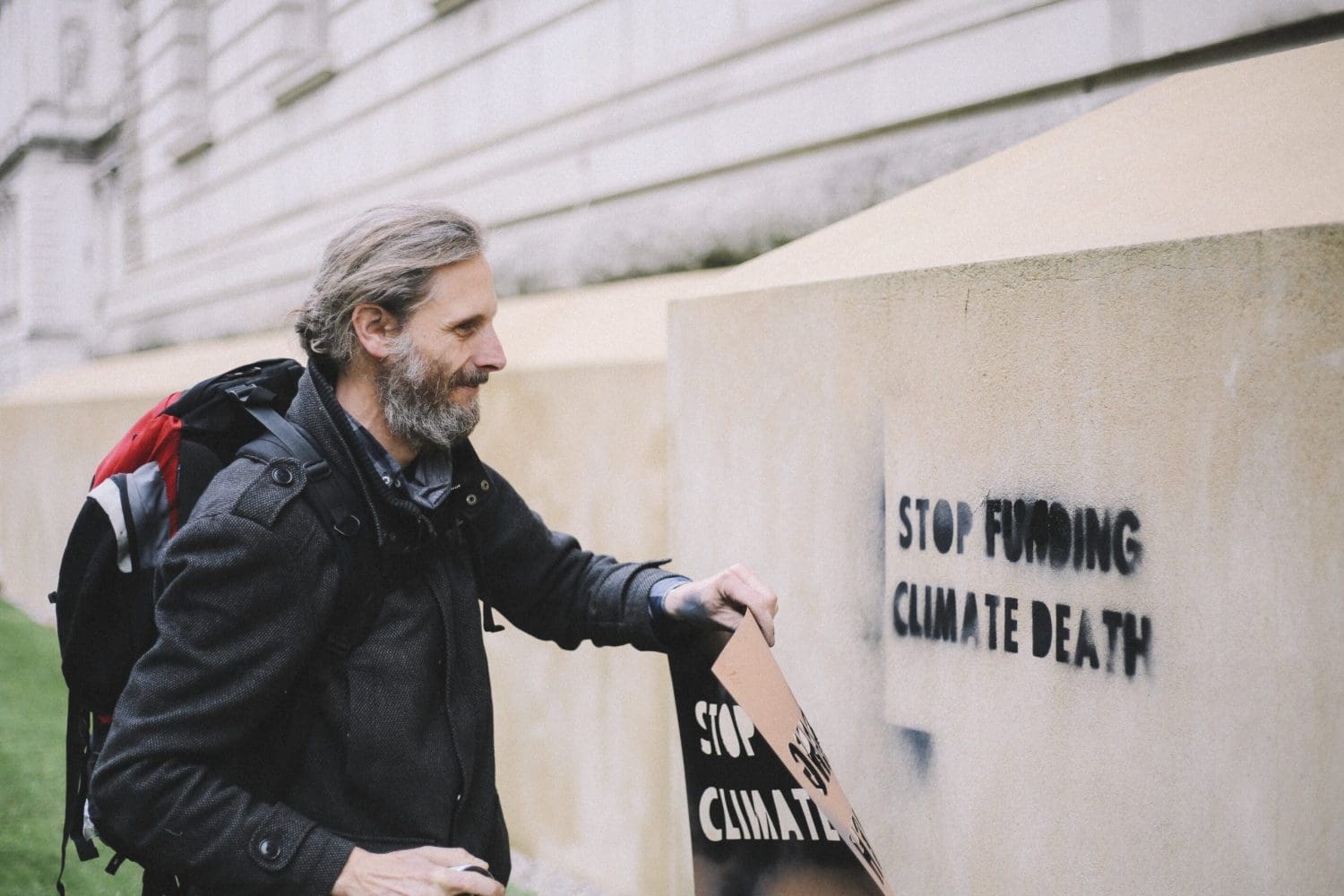 A stencil reading "STOP FUNDING CLIMATE DEATH"