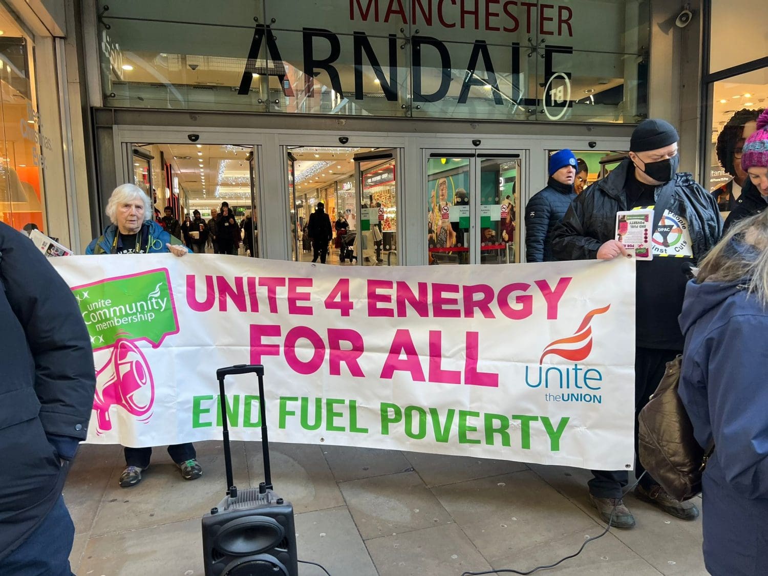 Protesters outside the Arndale Shopping Centre in Manchester with a banner that reads "Unite 4 Energy For All" 