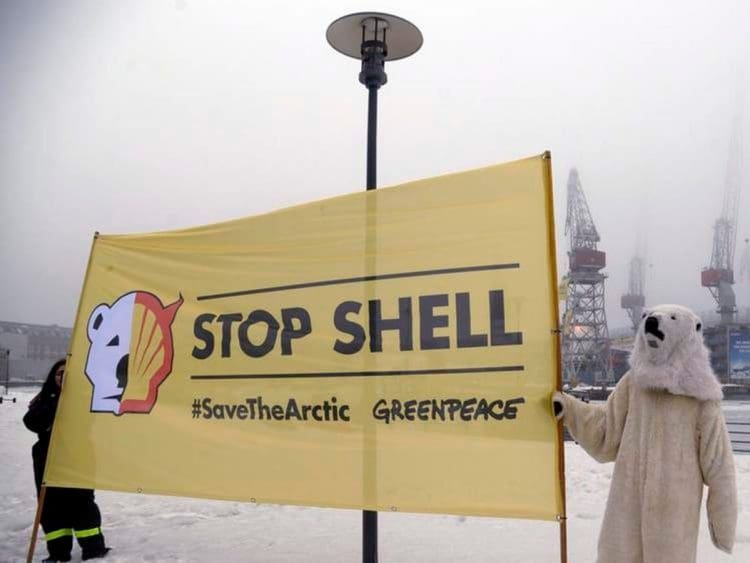 Greenpeace protesters with a stop Shell banner in the arctic one dressed as a polar bear net zero