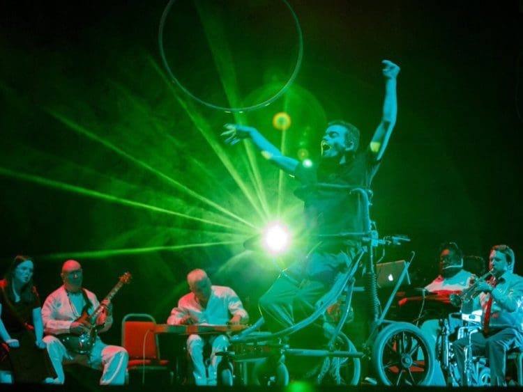 British Paraorchestra disabled musicians with a disabled dancer against a green light