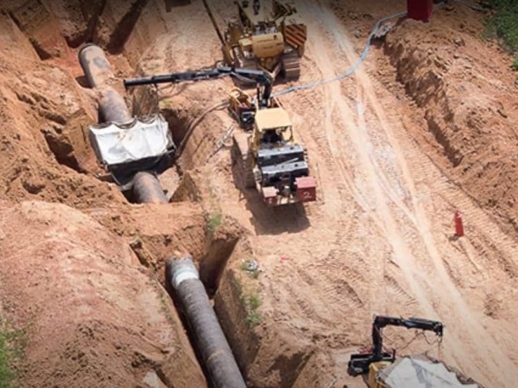 Construction workers lay an oil pipeline EACOP