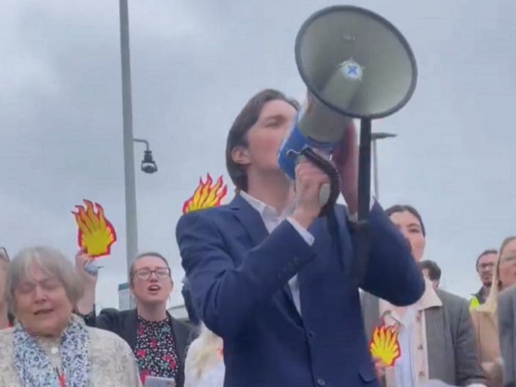 Protesters with a megaphone and Shell burning logos singing outside the company's AGM Shell AGM climate