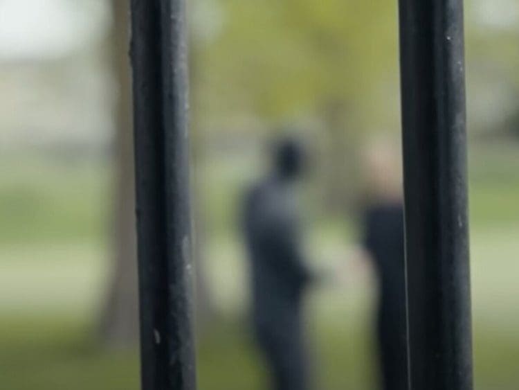 Prison bars, with someone in the distance blurred out behind Labour prison reform