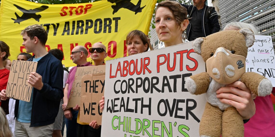 Protesters gather with banners and placards which read: "Labour puts corporate wealth over children's health."