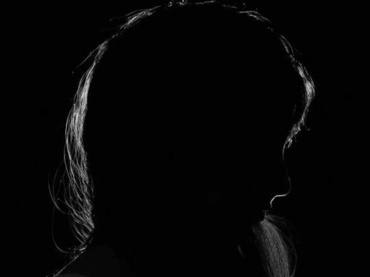 ME/CFS the shadow of a woman's face in a dark room