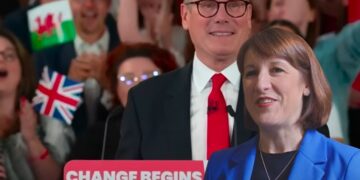 Starmer at the podium which reads: "Change begins" and Rachel Reeves laughing in front Labour