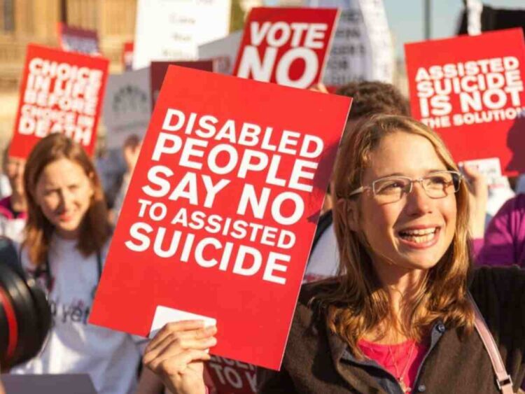 a protester holding a sign saying "disabled people say no to assisted suicide" assisted dying