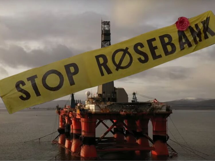 Yellow STOP ROSEBANK banner across a oil rig in the North Sea, with a red rose on top of the banner.