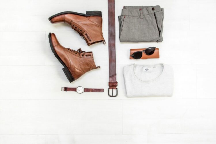 a pair of leather boots and some men's accessories lying on a white table